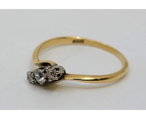 An 18ct. gold three stone diamond cross-over style ring, set row of three graduated diamonds (the centre stone approx. 0.25 c