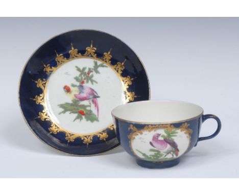 A Worcester cup and saucer, the cup with two gilt cartouches of Fancy Birds in a garden setting on a wet blue ground, the int