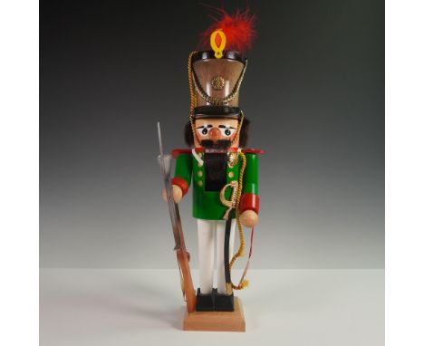 Handmade wooden nutcracker by Steinbach, depicting a soldier in a green coat with red cuffs, white trousers, and a tall plume