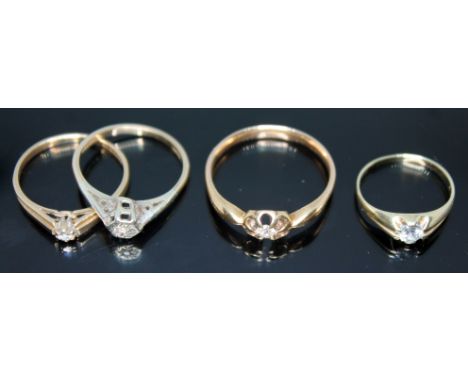 A group of four rings comprising two hallmarked 9ct gold diamond solitaires, another diamond solitaire unmarked and a ring ma