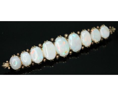 A precious opal brooch featuring nine opal cabochons, length 68mm, rafted in yellow metal, unmarked, gross wt. 7.53g.  Condit