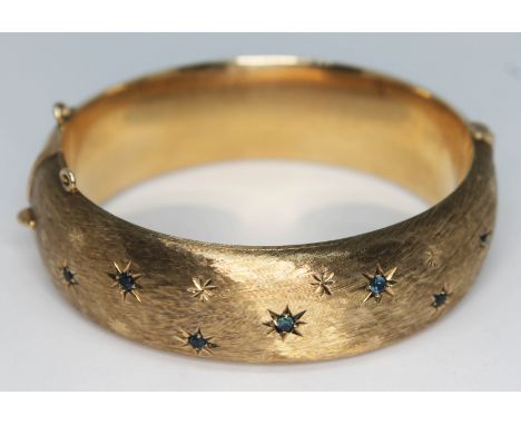 A hallmarked 9ct gold bangle set with blue stones, diam. approx. 56mm, gross wt. 33.35g.  Condition - missing safety chain an