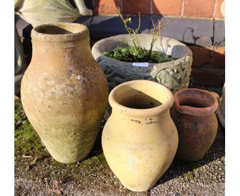 A small cast concrete planter with three terracotta pots.