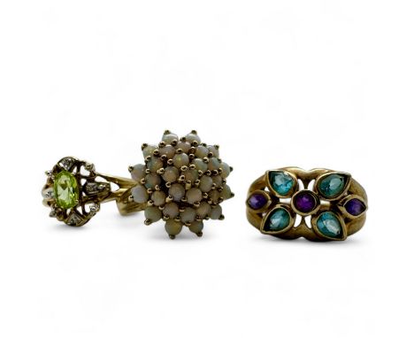 A trio of 9ct gold gem set dress rings. Featuring an opal cluster ring, size P; a peridot and diamond ring, size N; and an am