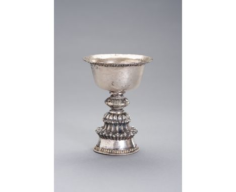 A SILVER BUTTER LAMPTibetan-Chinese, 19th century. The bowl incised with three Buddhist symbols, raised on a tall hollow mult