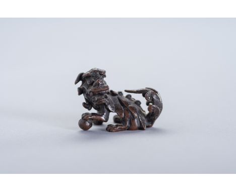 A MINIATURE BRONZE FIGURE OF A BUDDHIST LIONChina, 19th century. The bronze figure of a Buddhist lion, cast seated on its hau