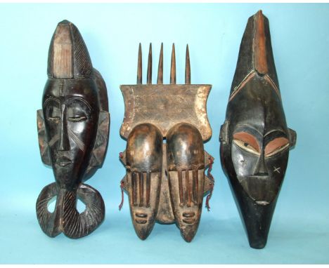 An African carved wood double-face mask with hatched decoration and surmounted by a 'comb', 51 x 25cm and two other African t