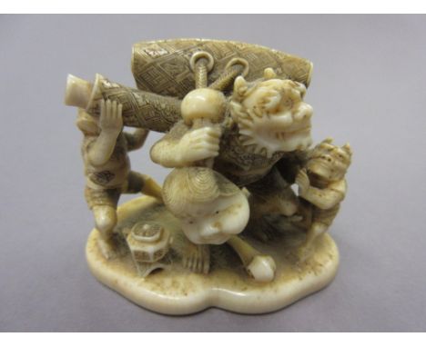 Finely carved Japanese Meiji period miniature okimono depicting three grotesque figures carrying a purse, netsuke, ojime and 