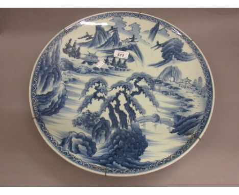 Chinese circular porcelain charger, blue and white decorated with a river landscape