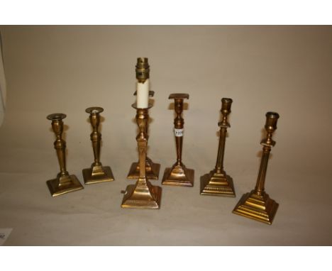 Three pairs of brass candlesticks on square set bases together with another similar table lamp