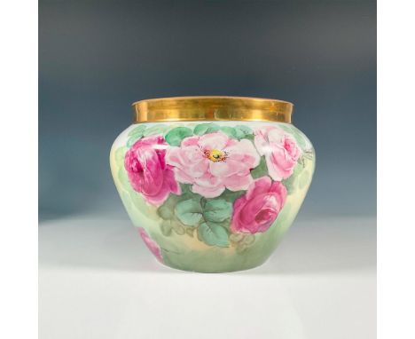 A hand painted Limoges planter decorated with bunches of roses and a gilt border, set on a cream surface. Artist signed C. He