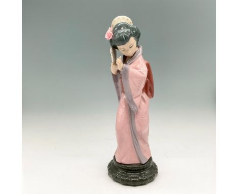 Glossy figural of timid Japanese girl colored in plum, rose and gray with flowers in her hair, holding a fan. Lladro backstam