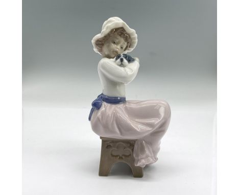 Glossy porcelain figure of a seated girl in a white hat holding a puppy. Nao backstamp. Issued: 1992Dimensions: 3.5"L x 3"W x