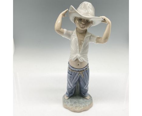 Glossy figural of boy with large cowboy hat, colored in blue, grey and white. Nao by Lladro backstamp. 02010182. Artist: Fran