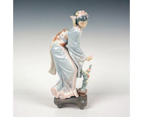 A glossy figure of a Japanese woman in a floral kimono over a potted plant. Lladro backstamp. This item has its original box: