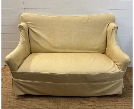 A two seater cream upholstered skirted sofa 