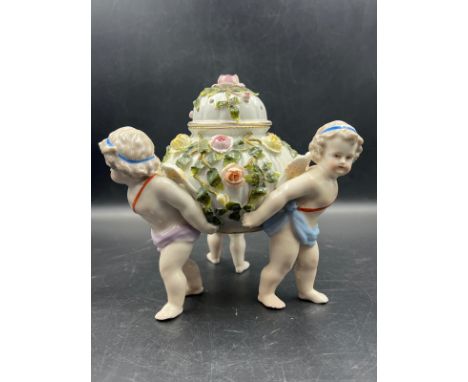 A Sitzendorf porcelain center piece with three cherubs supporting a lidded bowl decorated with flowers