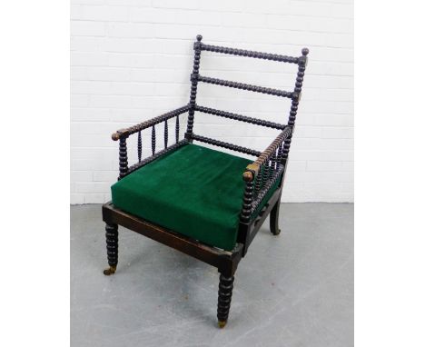 An ebonised bobbin turned open armchair with brass caps and castors, 98 x 60cm