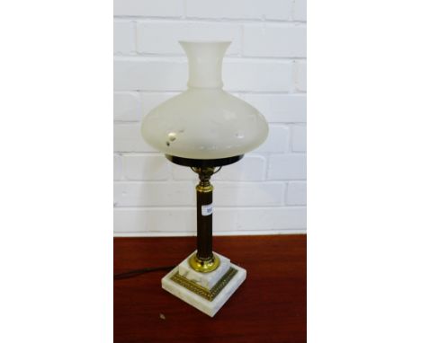 A brass stemmed table lamp with an opaque glass shade