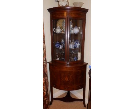 An inlaid mahogany corner cabinet, comprising a glazed bow front corner cupboard above a quadrant washstand with marquetry de