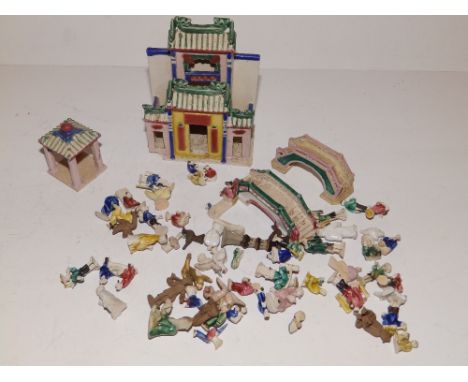 A collection of miniature Chinese ceramic figures with a building, two bridges and other items.