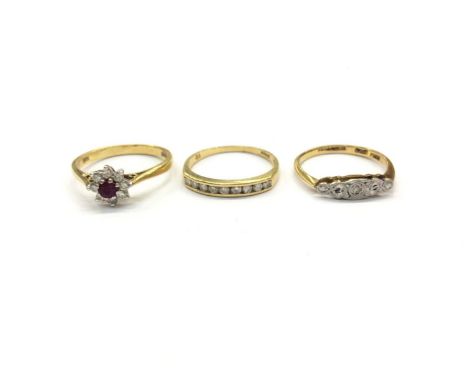 Three 18ct gold rings to include ruby and diamond flower head cluster, size M½, diamond channel set half eternity ring, size 