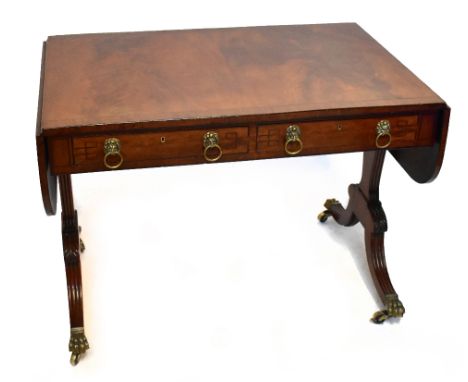 A late Regency mahogany and ebony strung sofa table with twin rounded flaps, lion head mask drop-ring handles to the two frie