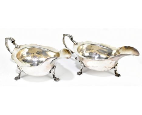 ISAAC COOKSON (probably); a pair of rare George II hallmarked silver sauce boats with cast rims, raised on three pad feet, wi