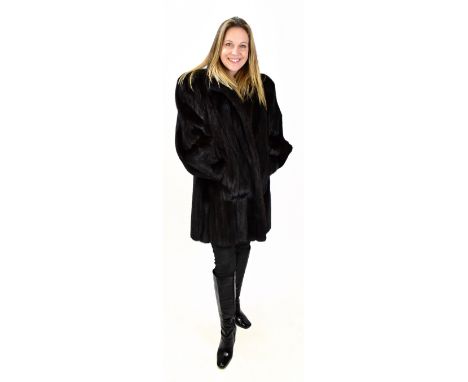 A good quality mid-length black/dark brown mink coat with three front hook and eye fastenings and lined in a black paisley-st