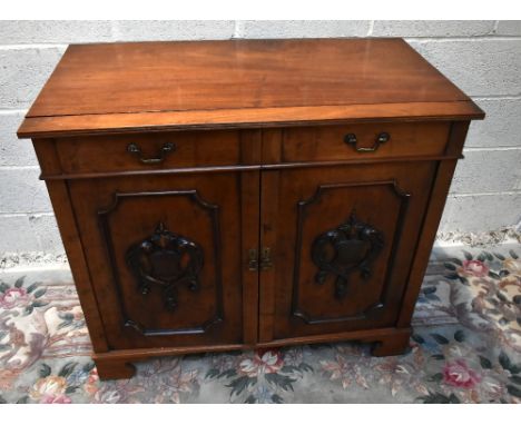 A mahogany side cabinet, the top made from a dining table leaf above a pair of drawers with twin cupboard doors raised on bra