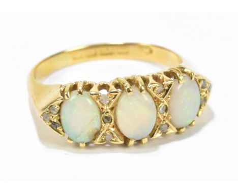 An 18ct yellow gold opal and diamond ring, the frame set with three oval opal cabochons and twelve diamond chips, size P, app