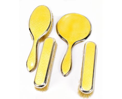 A George IV hallmarked silver and yellow enamel three piece dressing table set comprising mirror, hand brush and two clothes 