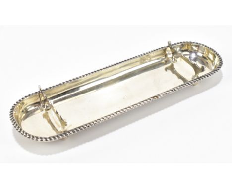 STOKES &amp; IRELAND; an Edward VII hallmarked silver pen tray of oval form with cast beaded rim, London 1904, length 22cm, a