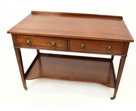 PHELPS LTD;&nbsp; a mahogany writing table with two drawers above undertier shelf, raised on spade feet, terminating on casto