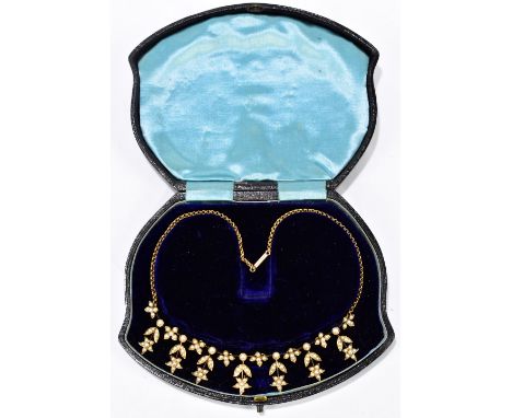 An Edwardian yellow metal and seed pearl necklace formed of seven floral dropped pendants, the central drop with facility to 
