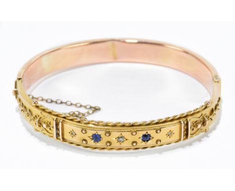 A 9ct yellow gold hinged snap bangle set with two small sapphire and three diamond chips to the upper section, approx 9.7g.Ad