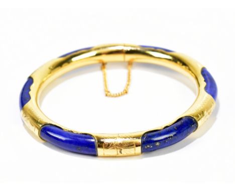 A yellow metal snap bangle set with lapis lazuli, diameter 7.5cm, internal diameter 6cm.Additional InformationThe piece is un