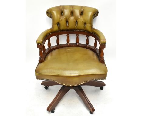 A reproduction revolving desk chair with green leather button back material and mahogany frame.