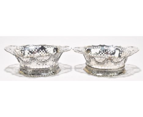 CHARLES STUART HARRIS; a pair of hallmarked silver baskets of oval form with cast and pierced decoration depicting flower hea