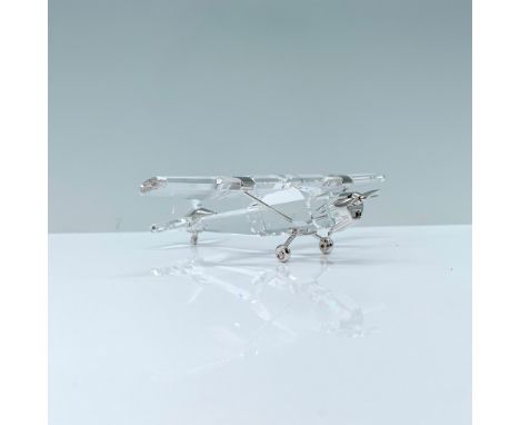 A clear crystal figure of an antique aircraft that is decorated with rhodium accents for the propeller, wheels, and struts. S