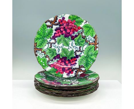 A set of 7 identical white plates with wavy borders that have a design of grape and grapevines taking over the plate. Copelan