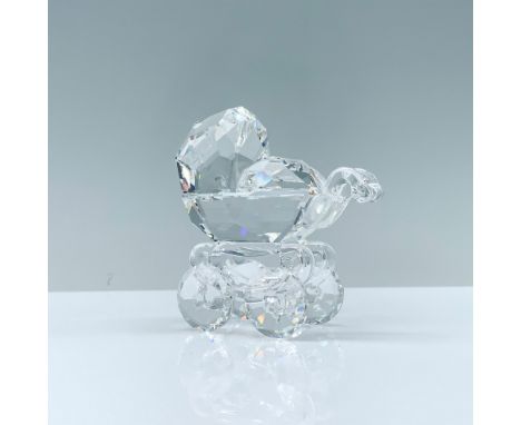 A clear crystal figure of a baby carriage featuring the handle and wheels with beautiful texture cuts. Swarovski backstamp. T