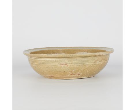 Chinese Yue-type stoneware basin glazed yellow or olive-green, likely Six Dynasties period. The wide bowl with rounded sides 