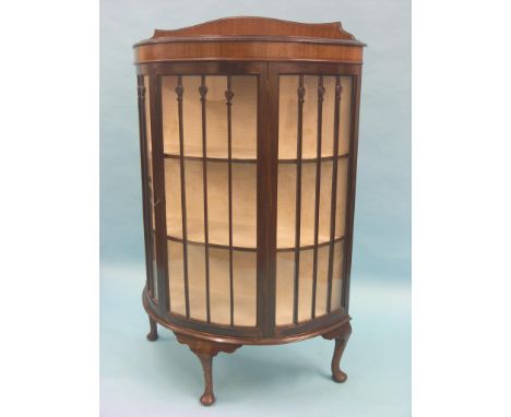 A George V mahogany display cabinet, half-round form with twin-shelf lined interior enclosed by astragal-glazed door, cabriol