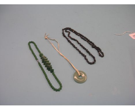 Garnet and jade, garnet bead necklace, jade bead necklace and a circular disc pendant, latter cracked