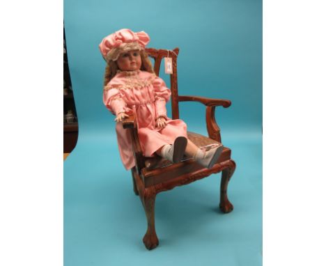 A child-size Chippendale-style armchair, with drop-in seat, and a bisque doll seated within