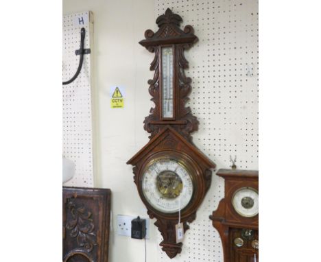 A late Victorian wheel barometer, ceramic dial signed Benetfink, Cheapside, London, with thermometer, oak case carved with ac