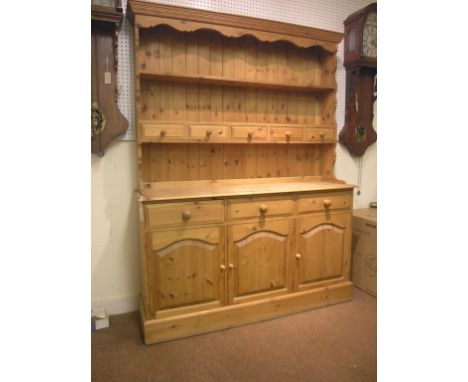 A waxed pine dresser, twin-shelf plate rack with five short drawers, panelled cupboard base with three drawers, 5ft.