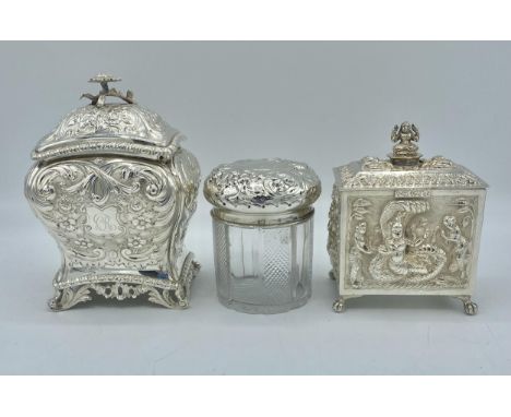 A sterling silver tea caddy with repousse decoration by Carrington &amp; Co London together with a a similar unmarked white m