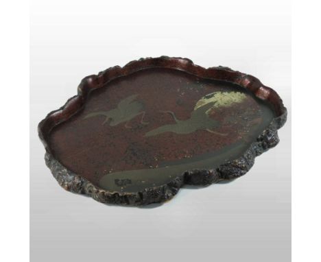 An early 20th century oriental lacquer serving tray, decorated with cranes, within a naturalistic tree trunk border, 61cm